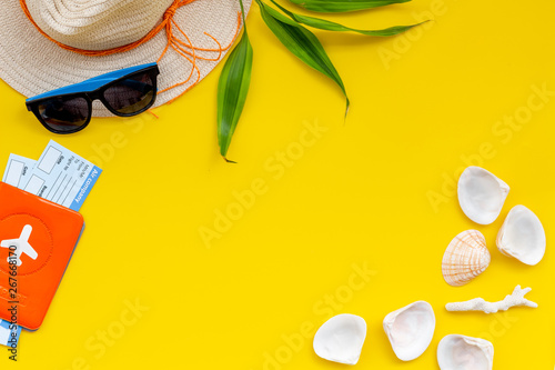 Straw hat, sun glasses, passport and tickets for sea vacation on yellow background top view copy space
