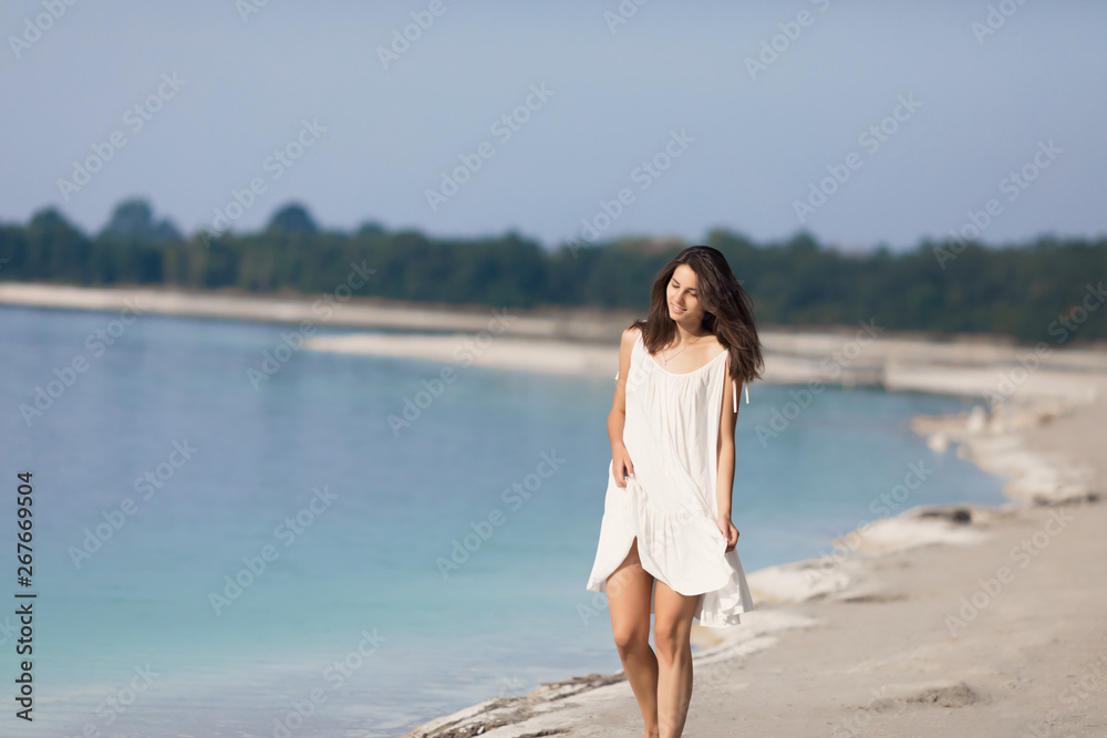 Young very beautiful girl with long hair in a white dress by the lake. The girl is enjoying the rest. Young very beautiful girl with long hair in a white dress by the lake. The girl is enjoying the rest.