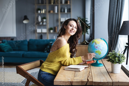 Smiling woman with a model of the globe selects a country for travel.