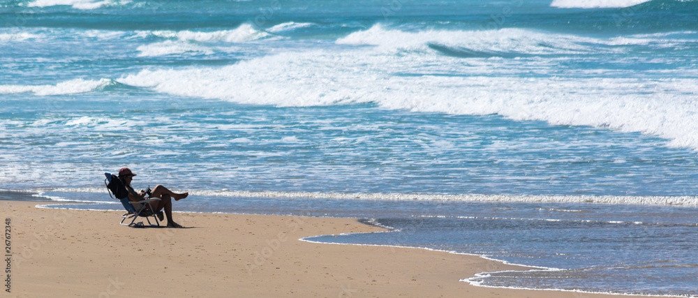 Pessoa sentada na cadeira em uma praia Pessoa sentada na cadeira em uma praia