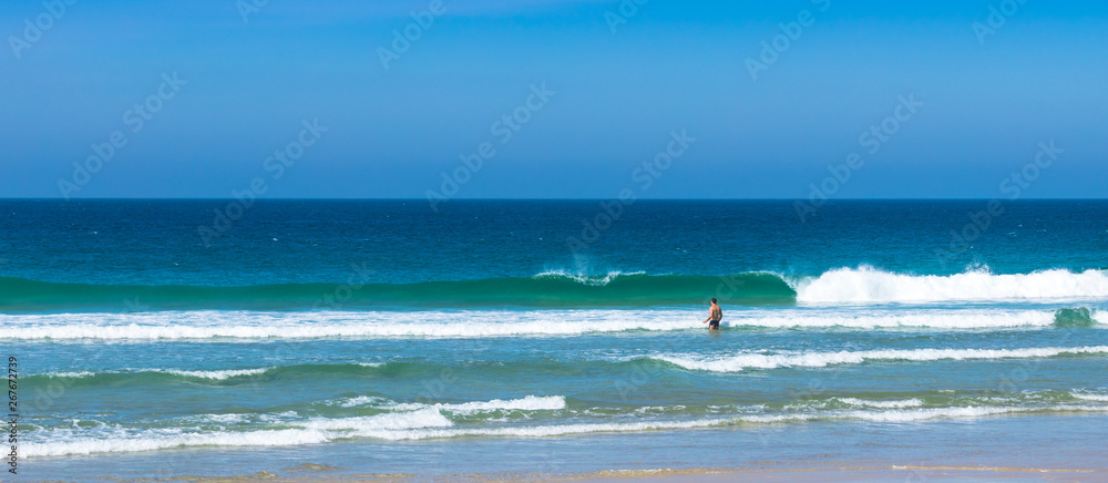 Uma pessoa na praia com ondas