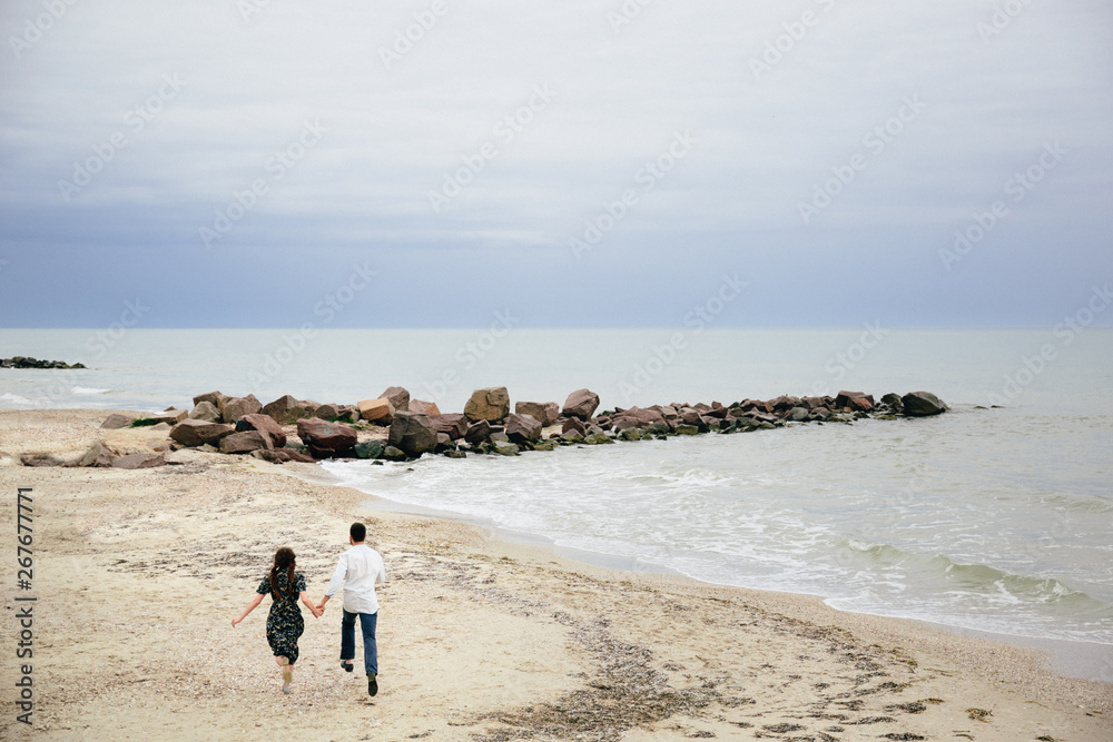 Picture of romantic young couple are walking by the sea shore
