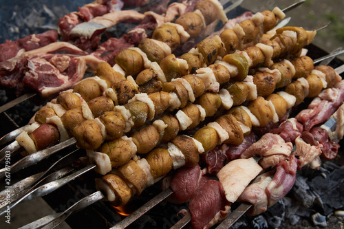 Preparation of shish kebab on skewers, close-up. BBQ grill with lamb meat and potatoes