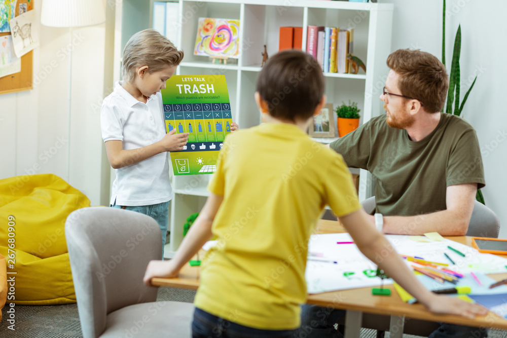 Obraz premium Active smart blonde boy in white t-shirt describing poster