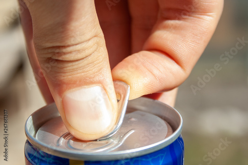 Man's hands opening can of beer close up at sunny day. Fresh drink at warm day. Alcohol drink.