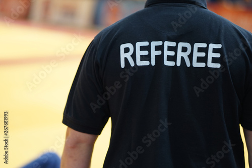 Back view of a man in a black shirt wit the referee title on his back at the tournament