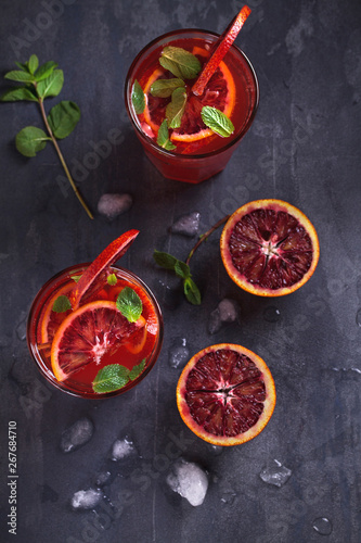 Two glasses of blood orange or red orange cocktail with slices of citrus fruits and mint - image