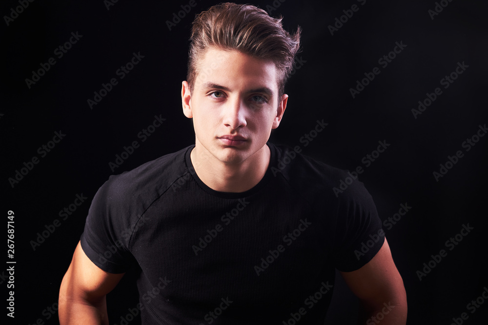 Naklejka premium Fashion portrait of elegant young handsome man isolated on black background
