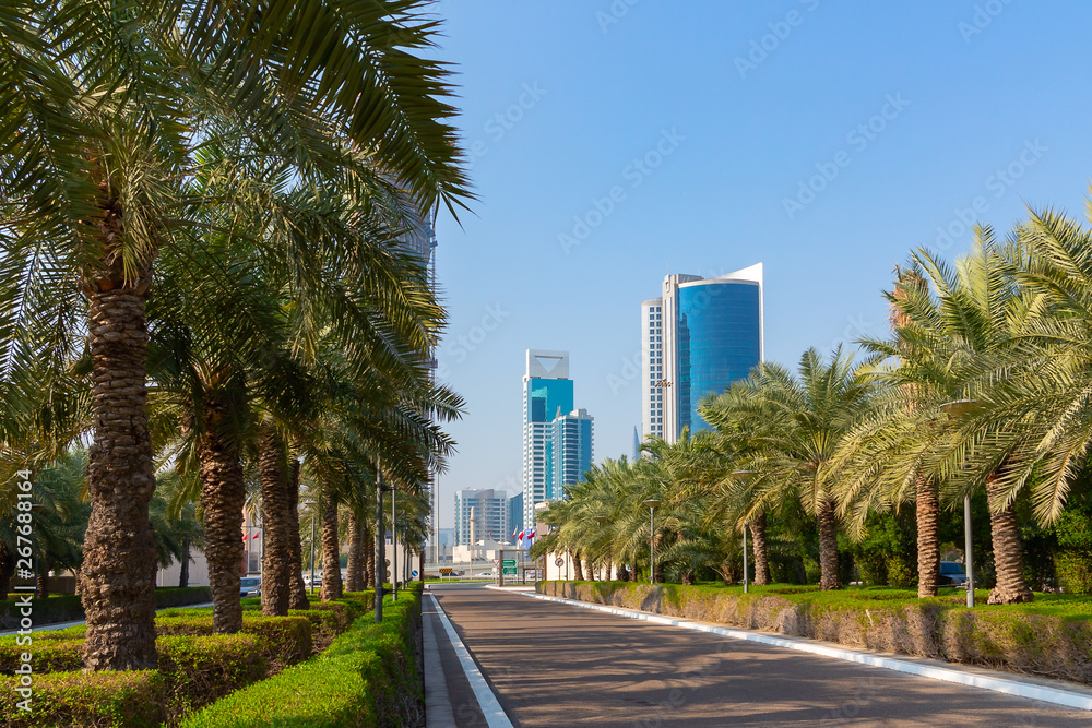 Palm avenue, asphalt road and skyscrapers in Manama city, Bahrain