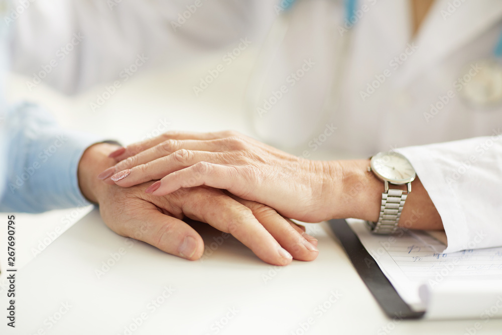 Closeup of female doctor holding patients hand during consultation, copy space
