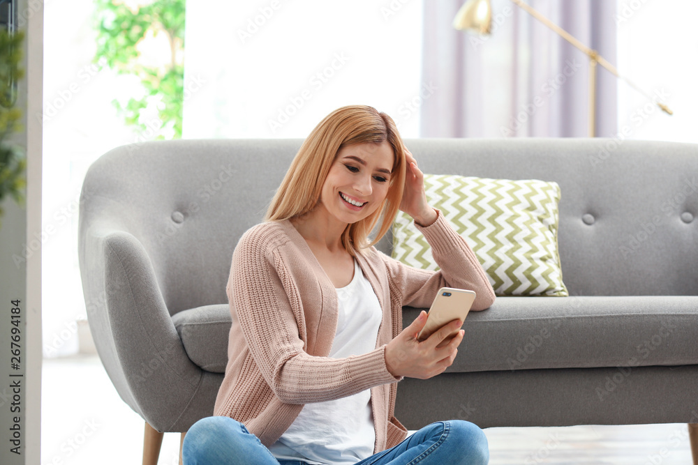 Woman using mobile phone for video chat in living room Woman using mobile phone for video chat in living room