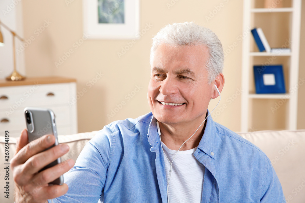 Mature man using video chat on mobile phone at home Mature man using video chat on mobile phone at home