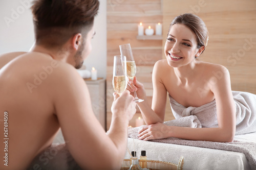 Romantic young couple with champagne in spa salon