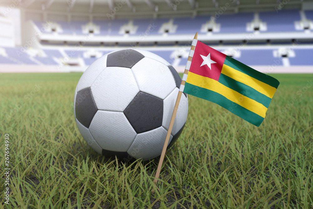 Togo flag in stadium field with soccer football