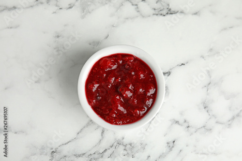 Bowl of cranberry sauce on marble background, top view photo