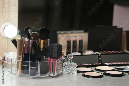 Different makeup products and accessories on dressing table in room interior