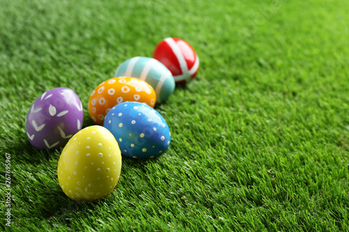 Colorful painted Easter eggs on green grass  space for text