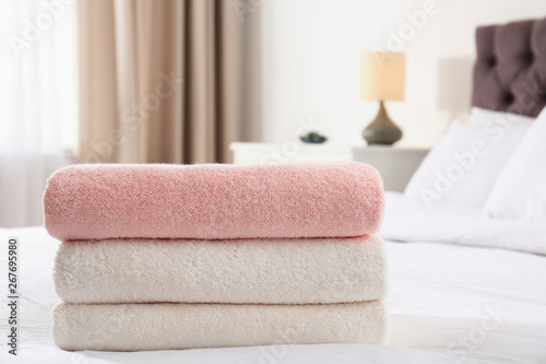 Stack of folded soft towels on bed in room. Space for text