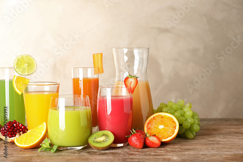 Glassware with different juices and fresh fruits on table. Space for text