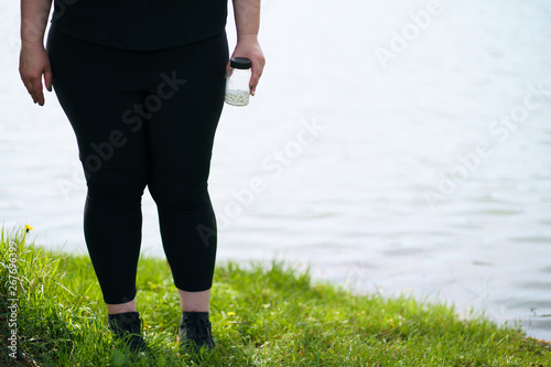 Overweight woman doubting to take slimming pills. Unhealthy way to be slim. Weight loss, pharmacy concept