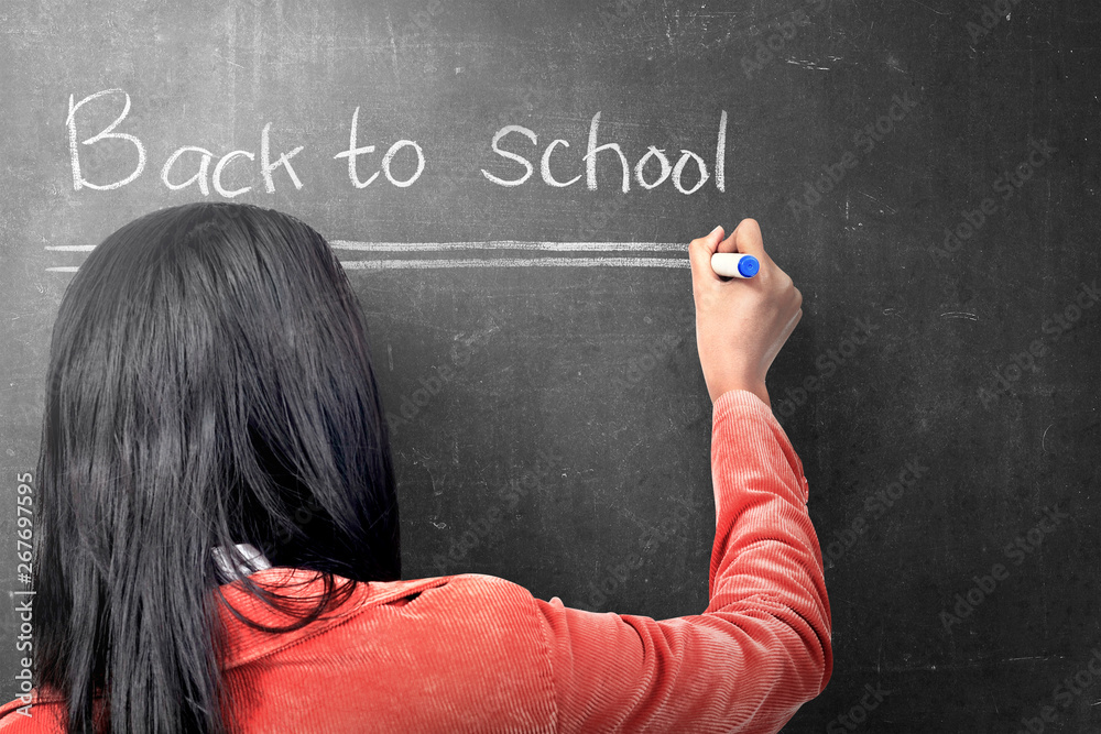 Rear view of asian student woman writing Back to School on the blackboard Rear view of asian student woman writing Back to School on the blackboard