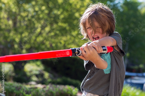 5 year old boy playing with a light saber outside
