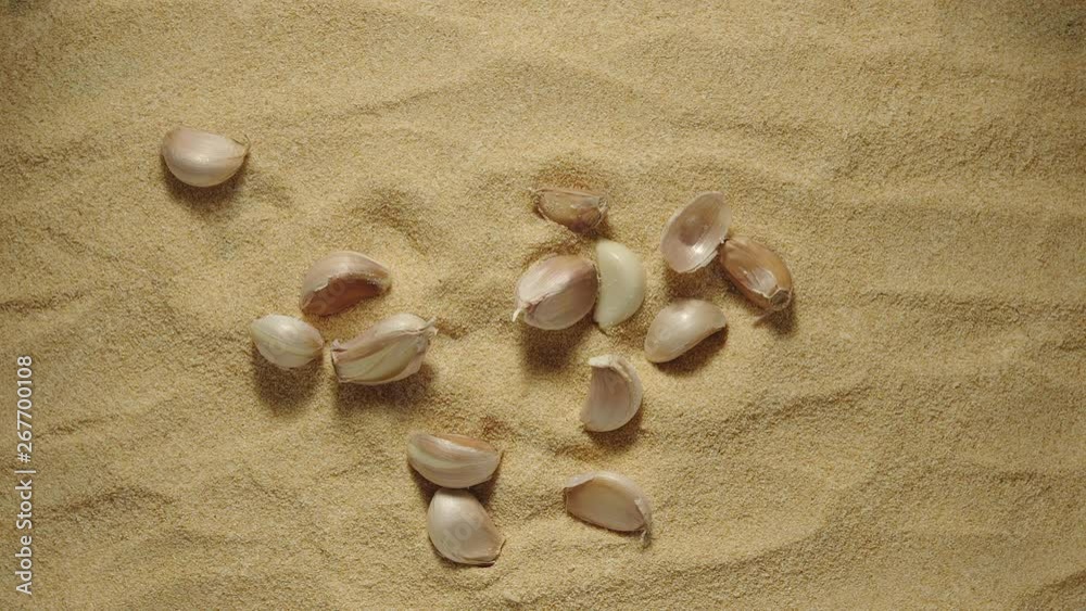 SLOW MOTION: Garlic cloves fall onto a heap of garlic powder SLOW MOTION: Garlic cloves fall onto a heap of garlic powder