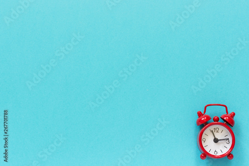 Red alarm clock in lower right corner on blue paper background. Minimal style Copy space Top view Template for your text, design
