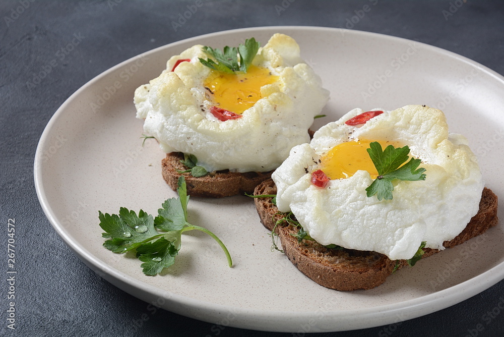Delicate baked egg. Orsini eggs in the cloud. French breakfast.Cloud egg on toast Delicate baked egg. Orsini eggs in the cloud. French breakfast.Cloud egg on toast