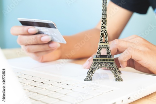 Woman's hands using laptop and credit card for booking or reservation hotel and flight for Paris