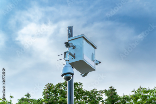 CCTV security camera, trees and blue sky.