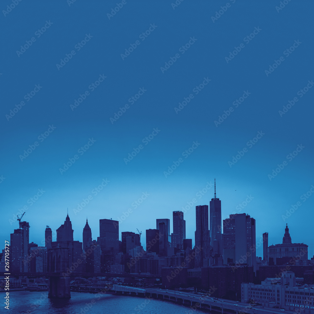 Blue New York City skyline buildings in Manhattan with Brooklyn Bridge and empty space in the background
