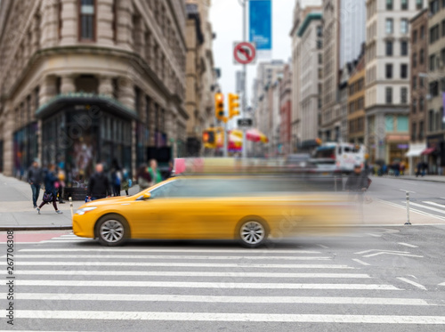 Motion blur of yellow taxi cab speeding through an intersection on 23rd Street in Midtown Manhattan New York City