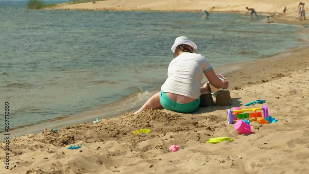 Girl builds a sand castle on the river bank Girl builds a sand castle on the river bank