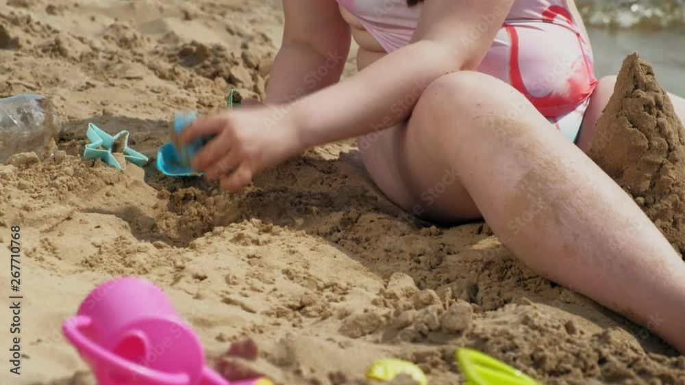 Girl builds a sand castle on the river bank Girl builds a sand castle on the river bank
