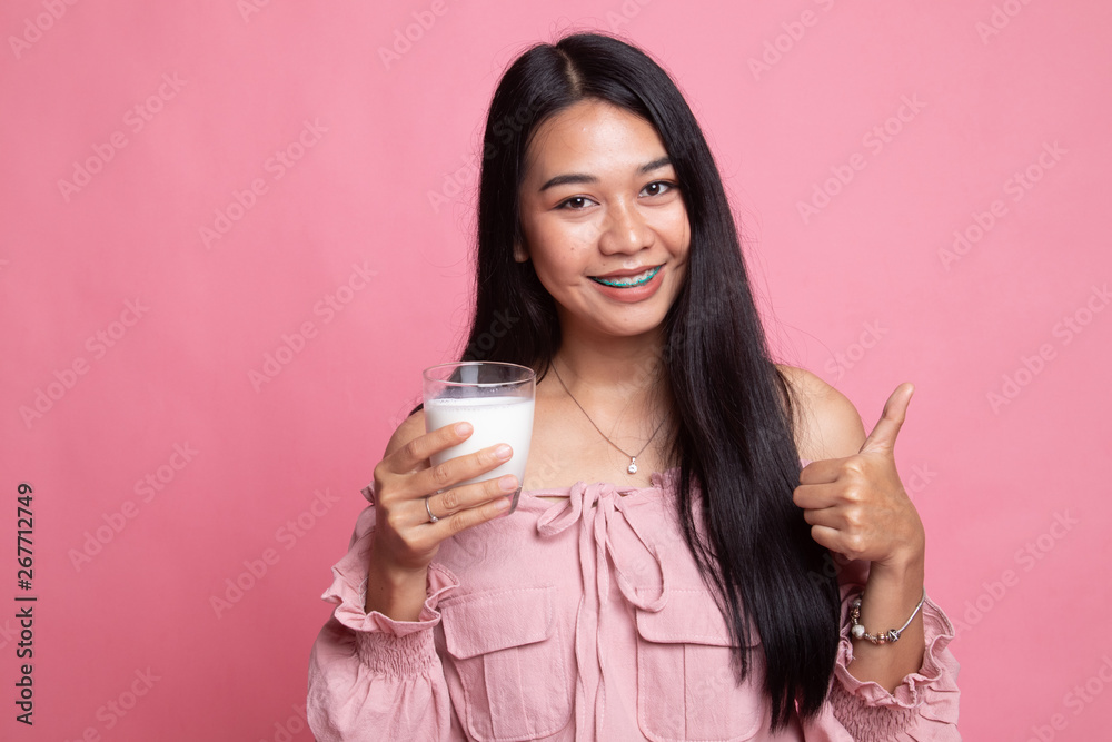 Healthy Asian woman drinking a glass of milk thumbs up. Healthy Asian woman drinking a glass of milk thumbs up.