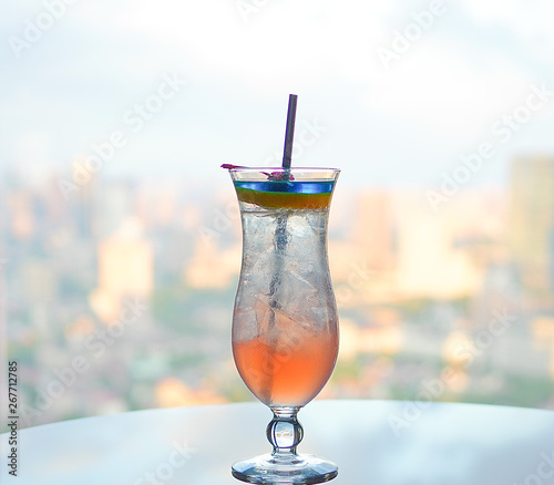 Colorful cocktail decorated with fruits near window cityscape view as background
