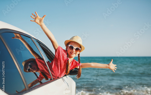 Photography happy child girl goes to summer travel trip in car.