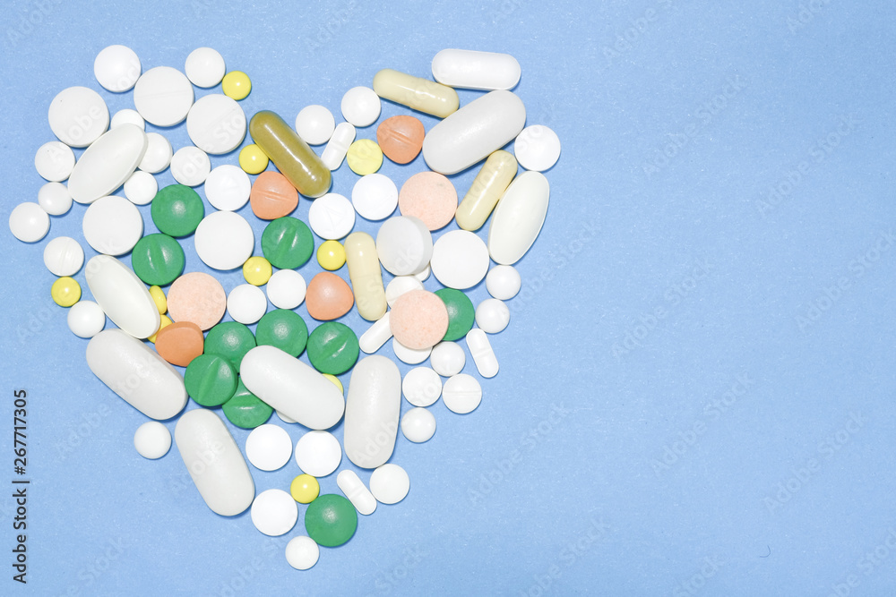 Heart shaped pills, White medicine pills on a blue. Heart shaped pills, White medicine pills on a blue.