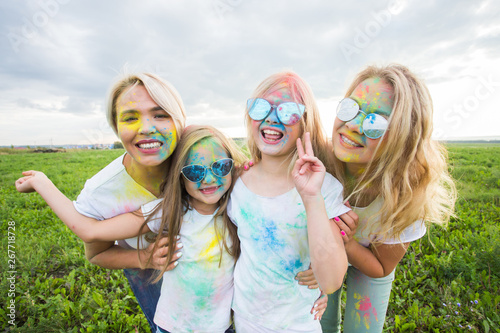 Friendship, holidays, color concept - Portrait of beautiful and happy friends covered in paint over nature background