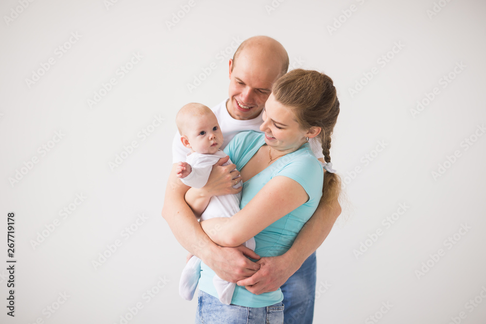 Proud mother and father smiling at their newborn baby daughter over white background with copy space Proud mother and father smiling at their newborn baby daughter over white background with copy space