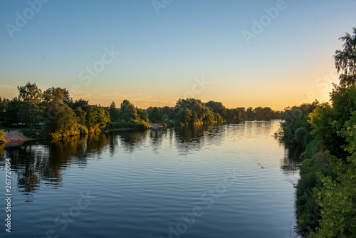 reflections of shore trees in the calm water of a lake © Martins Vanags