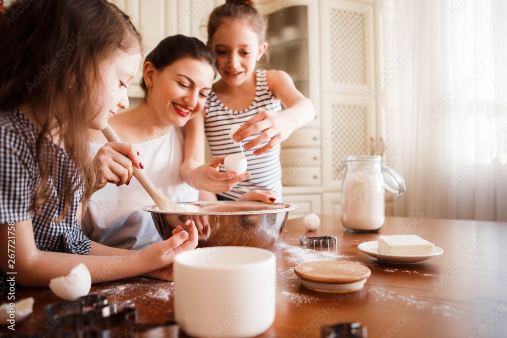 Mom and daughters prepare pastries in the bright classic kitchen. Creative mess on the table. Life style. Mom and daughters prepare pastries in the bright classic kitchen. Creative mess on the table. Life style.