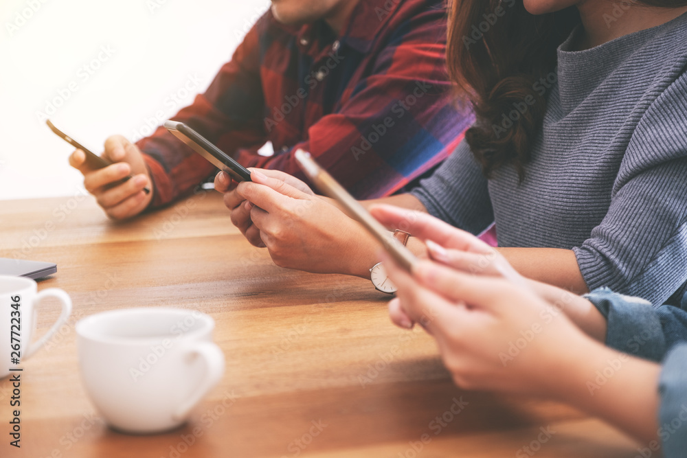Group of people using and looking at mobile phone and tablet pc while sitting together Group of people using and looking at mobile phone and tablet pc while sitting together