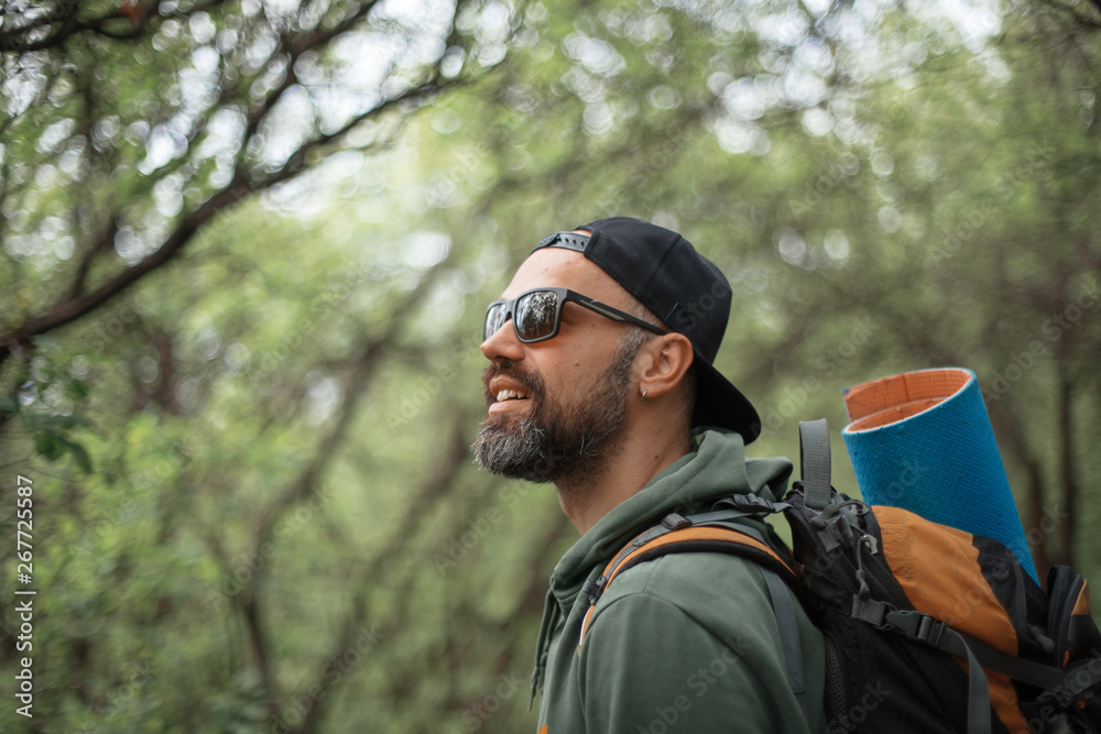 A young guy with a backpack in the cap, traveller in the woods, Hiking, Forest, Journey A young guy with a backpack in the cap, traveller in the woods, Hiking, Forest, Journey