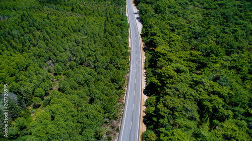 Aerial view from above of country road through the green summer forest in summer Turkey. Top view of the asphalt road and dense green forests