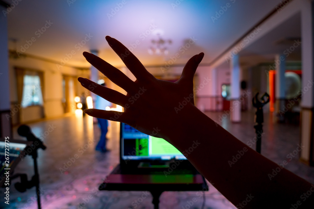 Female's hand over the dancing hall background. Recording studio mixer on digital tablet and microphone on the blurred background. Close-up hand.