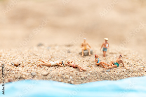 Miniature people wearing swimsuit relaxing on the beach , Travel and Summer concept