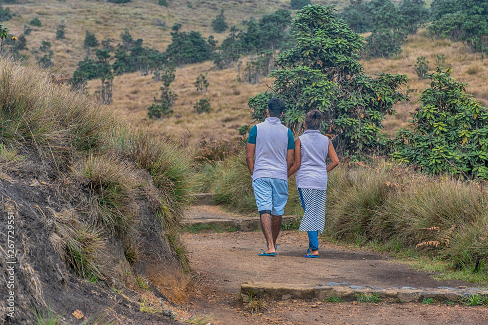 A Beautiful Young Love Happy Couple in Casual Travel Clothing Walking Arm in Arm on a Trail in Horton Plains, Nuwara Eliya Sri Lanka