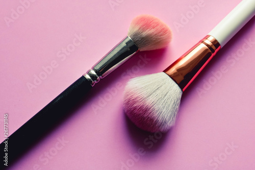 Two used make up brushes on the pink background. Fashion concept.